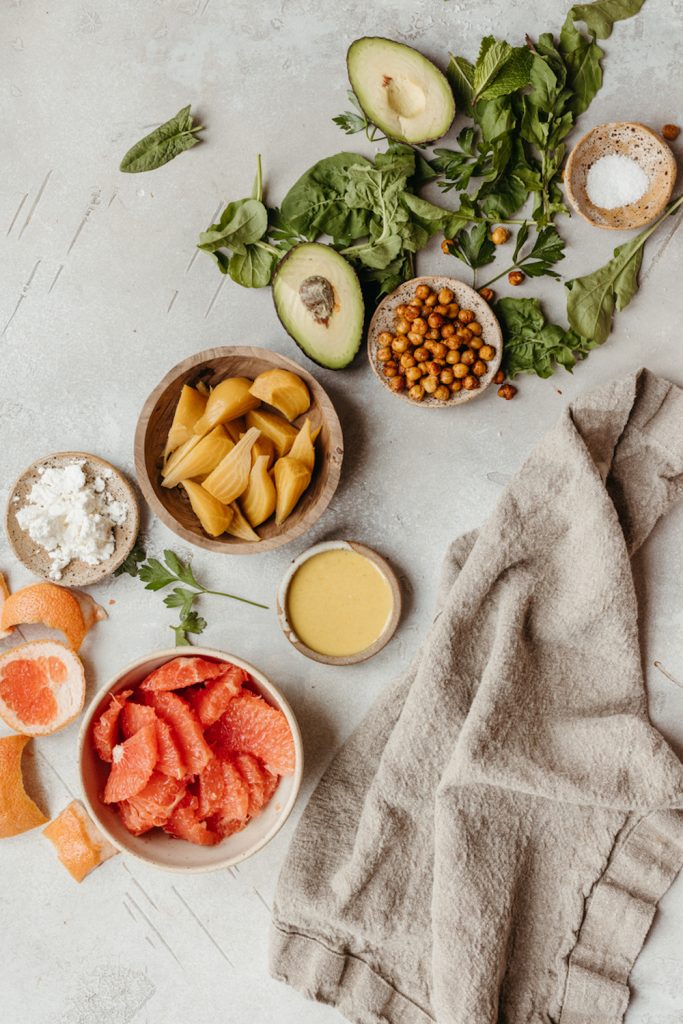 Avocado, herbs, chickpeas, golden beets, and grapefruit slices in bowls.