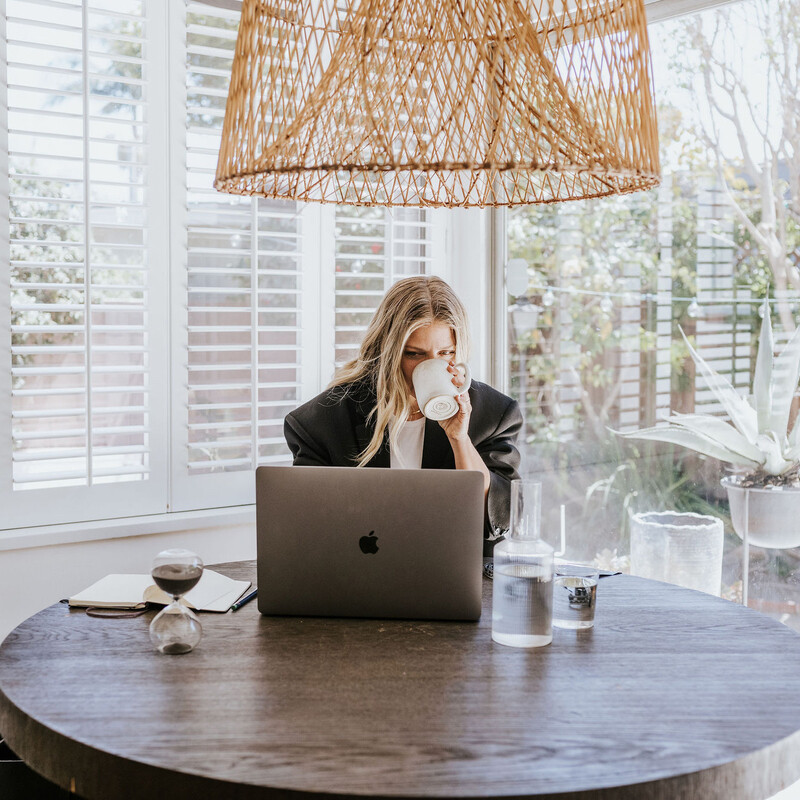 Woman drinking coffee at desk.