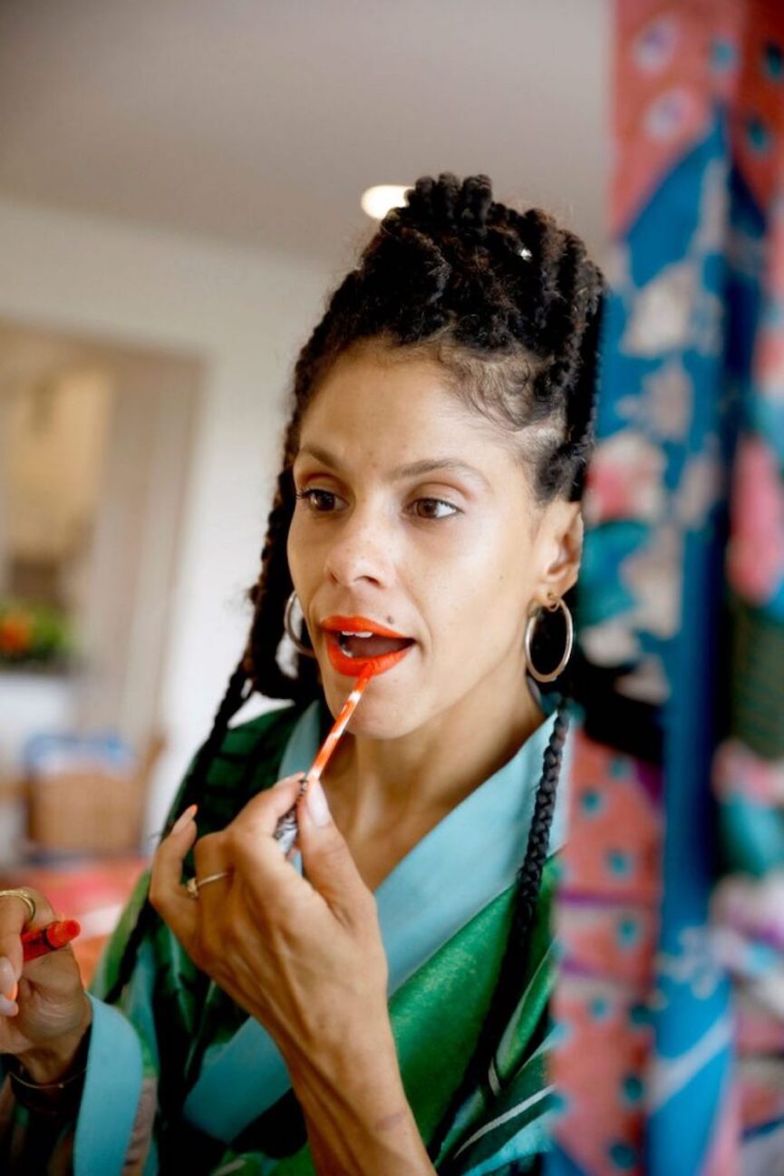 Woman applying lip stain in mirror.