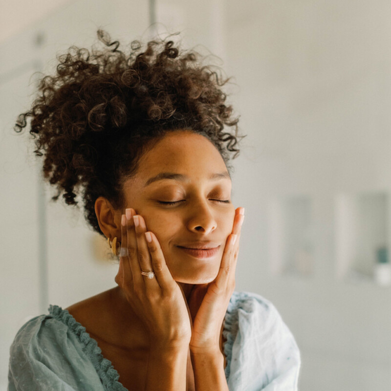 Woman washing face in mirror.