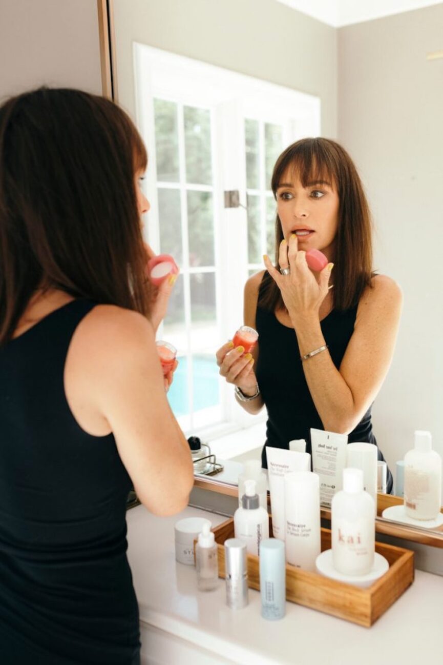 Catt Sadler applying makeup in mirror.